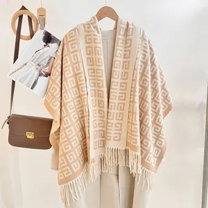 Close-up of beige knit shawl with geometric pattern and long fringe tassel detail