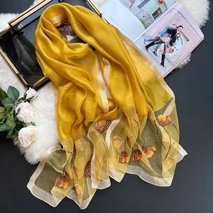 Detail of yellow silk blend scarf with floral embroidery and sequins on fur background