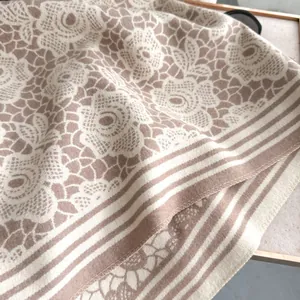 Detailed macro view of beige cashmere feel scarf with rose floral lace pattern and soft texture