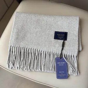 Close-up of light gray wool scarf with fringe and 2024 classic brand label details