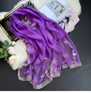 Detail of silk scarf with floral embroidery and glitter edges on elegant display
