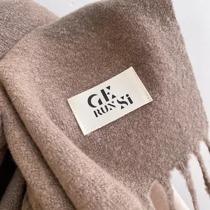 Detailed macro view of camel knit scarf texture with fringe and branded woven label