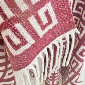 Macro shot of knit scarf with burgundy greek key pattern and soft fringe edge detail