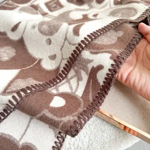 Detailed close-up of thick plush scarf fabric with cute bear pattern and stitched edges