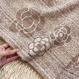 Macro detail of thick camellia weave pattern and long tassels on beige scarf