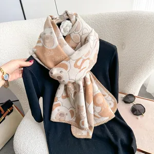 Close-up of thick beige and brown knit scarf with cartoon bear jacquard pattern