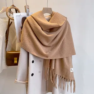 Detailed close-up of thick camel winter scarf with fringe on a beige wool coat