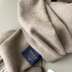 Macro detail of high-quality wool scarf with soft twill weave texture and elegant brand label