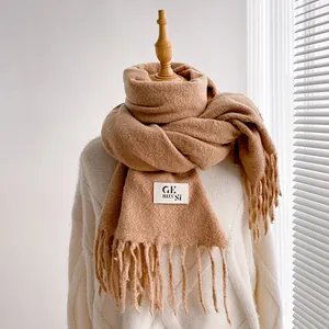 Detailed macro view of the thick brown scarf fabric with elegant fringe and white woven label