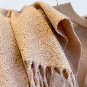 Close-up of beige thick bouclé scarf texture with decorative fringe tassels detail