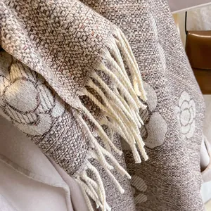 Close-up of beige tweed camellia scarf with thick knit texture and fringe details