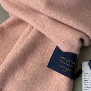 Macro detail of pink wool scarf texture showing fine twill weave and product label