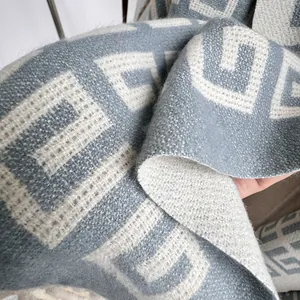 Close-up of thick knit cashmere feel scarf with grey and beige geometric pattern