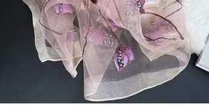 Detail of silk blend shawl featuring purple butterfly embroidery and pearl accents