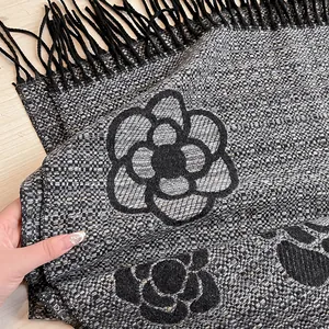 Close-up of tweed scarf texture with camellia flower pattern and fringe details