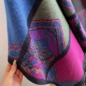 Detail of bohemian knit shawl with colorful geometric patterns and black fringe tassels