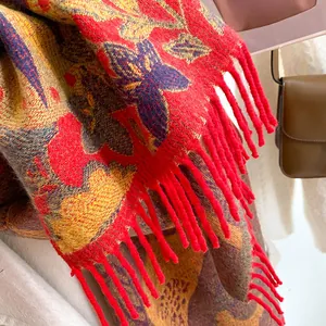 Détail d'un châle jacquard rouge et or avec glands décoratifs et texture douce et chaude