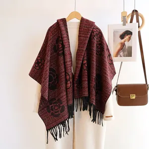Detail of burgundy knitted shawl with black camellia patterns and long fringe tassels