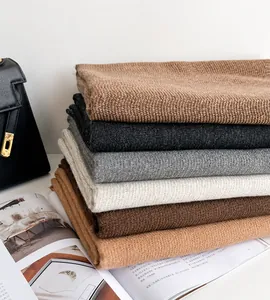 Fashionable soft knit scarves in various solid colors stacked on a stylish background