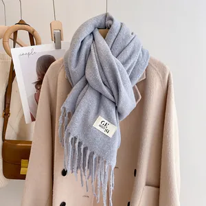 Close-up of light blue scarf with soft texture, fine fringes and stylish woven label