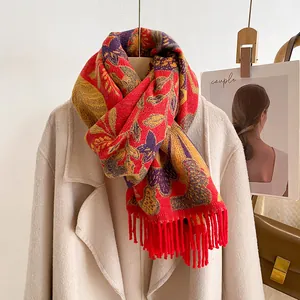 Détail d'une écharpe rouge à motifs floraux violets et pompons à franges douces