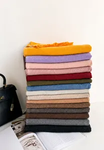 Vertical stack of multi-color cashmere-style knit scarves with tassel edges in various hues