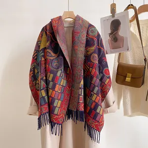 Detail of vintage paisley pattern shawl with fringe on beige coat with brown leather bag