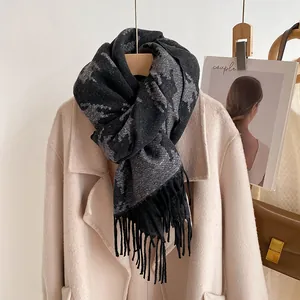 Detailed view of dark grey houndstooth wool scarf with fringes on beige coat