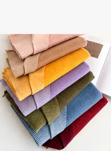 Detail of stacked cashmere-like scarves showing soft woven texture and fringe trim
