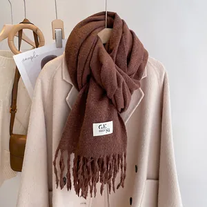 Detail shot of coffee brown tassel scarf showing soft fringe texture and woven brand label