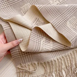 Detail view of thick beige and brown checkered jacquard scarf with decorative tassels