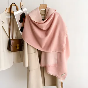 Detail of pink knitted shawl with fringes styled over a beige wool coat