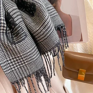 Detail of black and white checkered scarf with fringe trim and soft woven texture