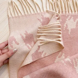 Close-up of thick pink houndstooth wool scarf featuring long decorative tassels