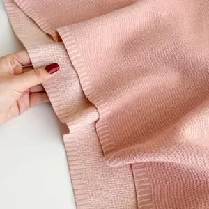 Close-up of pink cashmere-like scarf fabric showing soft knit texture and ribbed edge