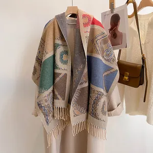 Detail of bohemian knit shawl featuring ethnic patterns and fringe hanging on a coat