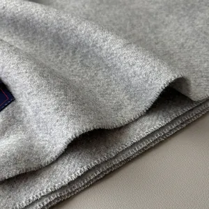 Detailed close-up of soft grey wool scarf texture with fine stitching and fabric label
