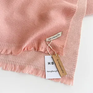 Close-up of pink cashmere-like scarf showing soft rib-knit texture and fringe details