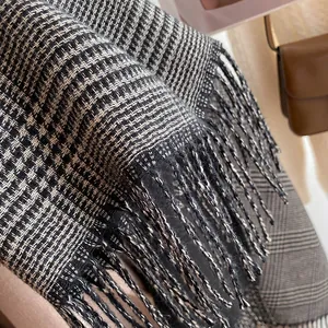 Detailed view of black and white houndstooth scarf with elegant tassel edges and soft texture
