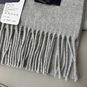 Detailed close-up of grey wool scarf with soft fringe tassels and authentic product tags
