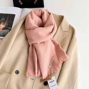 Detail of pink knitted cashmere-like scarf with fringe edges on beige wool coat