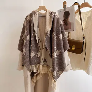 Detailed view of houndstooth wool scarf with fringe trim draped over a beige coat