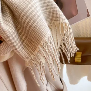 Detail of beige and brown plaid scarf featuring soft fringe trim and knit texture
