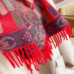 Detail of red and purple jacquard knit scarf with tassels paired with a beige coat