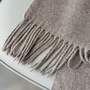 Close-up of soft brown wool scarf featuring elegant fringe trim and plush texture