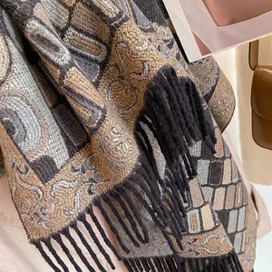 Detail shot of vintage geometric jacquard pattern and thick black tassels on a warm shawl