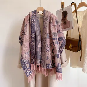 Close-up of thick core-spun yarn shawl with paisley prints and pink tassel details