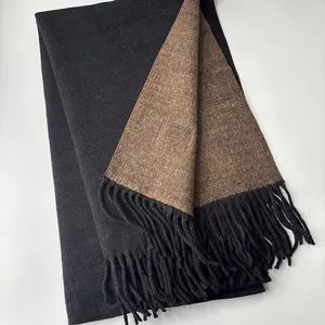 Detail view of double-sided wool scarf showing solid black and brown fabric with long tassels