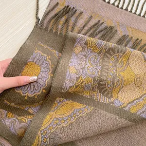 Close-up of bohemian floral jacquard knit shawl with long fringe tassels on wood background