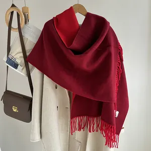 Detail of burgundy fringe scarf on a wooden hanger with a brown leather bag